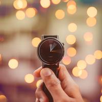 Watch by Saffu on Unsplash A person holding up a watch - pretty lights in background